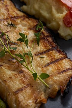 Ahşap zeminde kaynamış sebzeli bir tabak uskumru.