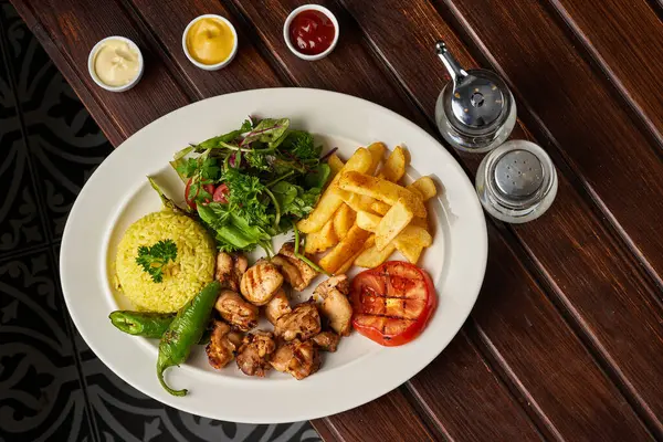 Izgara tavuk eti tabağı, pilav, patates ve sebze.