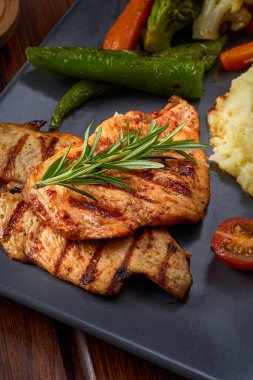 Bir tabak ızgara tavuk göğsü, patates püresi ve biberiye.