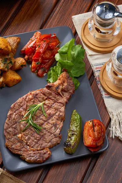 Biberiyeli, patatesli ve ızgara sebzeli biftek tabağı.