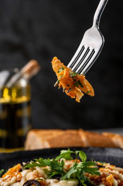 Peynirli, zeytinli ve çatallı makarna tabağının yakın çekimi.