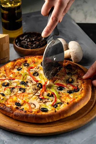 Bir insan tarafından dilimlenmiş sebze ve peynirli pizza.