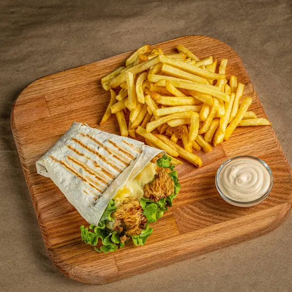 Tahta zeminde patates kızartması ve sos ile çıtır çıtır tavuk dürümü