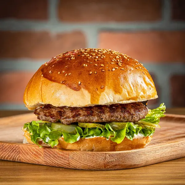 Çedar peynirli dana burger, ahşap zeminde soğan ve mantar.