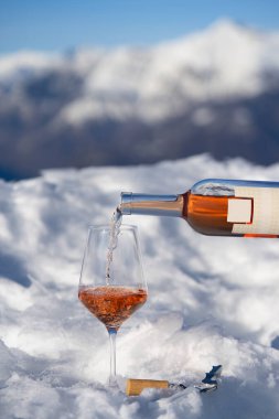 Karlı bir dağda bir şişe şarap ve bir kadeh şarap