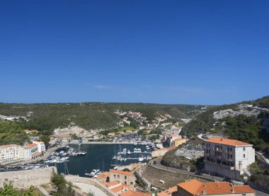 Suda birkaç teknesi olan bir marina ve kırmızı çatılı bir bina.