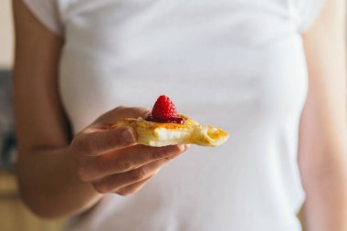 Camembert peyniri ve ahududu reçeli ile doldurulmuş küçük bir puf böreği tutan bir kadının elini kapat. Taze ahududu ile süsle..