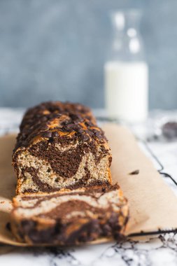 Taze pişmiş, şekersiz muz ve kepekli un ile yapılmış çikolatalı mermer somun parşömen yüzeyinde duruyor.