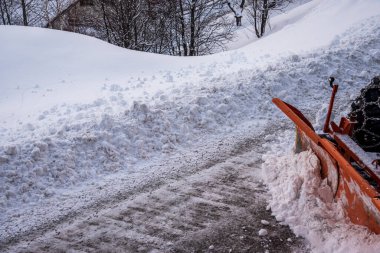 Alplerdeki bir köyde caddeyi taze kardan temizleyen traktörün kısmi görüntüsü