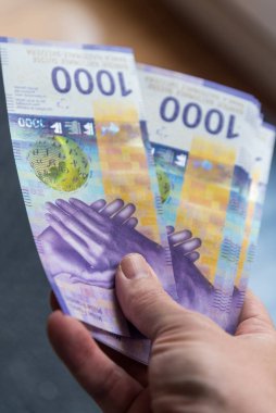 İsviçre frangı banknotlarını tutan el.