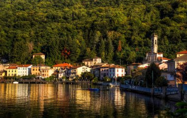 Porto Ceresio 'nun manzarası akşam ışığı ve su yansıması.