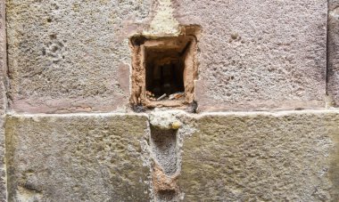 İçi sigara izmariti dolu taş bir duvarda bir delik.