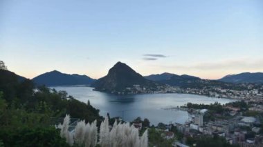 Gölde ve Lugano şehrinde gün doğumunun güzel bir zamanı. Arka planda San Salvatore dağı ve oradan geçen bulutlar.