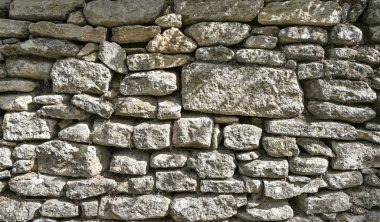 Fransa 'daki kırsal taştan bir duvarın detaylı bir görüntüsü istiflenmiş kayaların dokularını ve desenlerini gösteriyor.