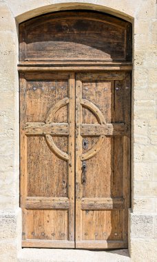 Bir çift eski ahşap kilise kapısı dekoratif oymalar ve yıpranmış bir yüzey, Fransa 'da taş bir kemer yoluna kurulmuş.