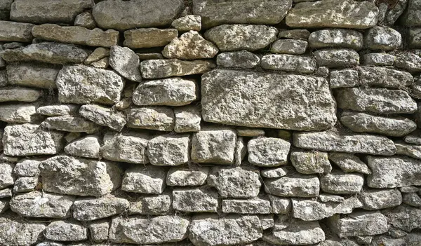 Fransa 'daki kırsal taştan bir duvarın detaylı bir görüntüsü istiflenmiş kayaların dokularını ve desenlerini gösteriyor.