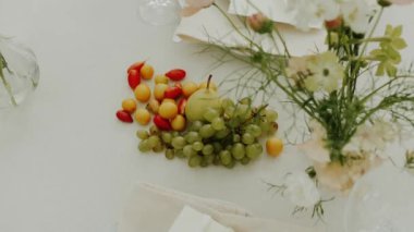 Serada sunulan ve pastel çiçeklerle dekore edilen düğün masasının yakın plan resmi. Minimalist doğal düğün yemeği, tabaklar ve şarap bardakları için. Çekim yapan kimse yok, yavaş çekim. Yüksek kalite