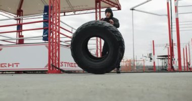 Eğitim motivasyonu. Spor salonunun dışında spor yapan bir sporcu. Dışarıdaki güçlü formda adam eğitimi büyük bir lastiği kaldırıyor. Yüksek kalite 4k görüntü