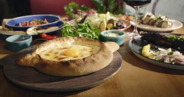 Doğu mutfağı. Gürcistan ulusal mutfağı, restoranda masada yemek. Salata, khachapuri, patlıcan aperatifleri. Orijinal geleneksel yemekler. Yüksek kalite 4k görüntü