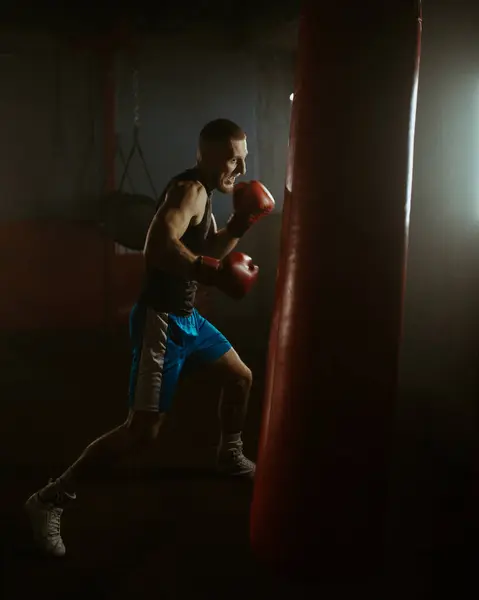 Sport motivation, portrait shot of athlete man boxing in the old school gym. Fit strong man training with boxing bag. High quality 4k footage