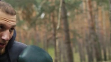 Boksör sporcu ormanda antrenman yapıyor. Eski moda açık hava kum torbasıyla antrenman. Yüksek kalite 4k görüntü