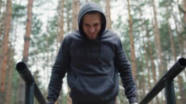 Açık hava antrenmanı. Genç formda adam ormanda antrenman yapıyor. Jimnastik açık hava eğitimi. Adam dışarıda barfiks çekiyor. Yüksek kalite 4k görüntü