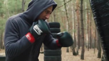 Boksör sporcu ormanda antrenman yapıyor. Eski moda açık hava kum torbasıyla antrenman. Yüksek kalite 4k görüntü