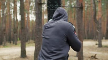 Boksör sporcu ormanda antrenman yapıyor. Eski moda açık hava kum torbasıyla antrenman. Yüksek kalite 4k görüntü