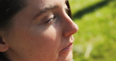 Güzel kız fast food yiyor. Parkta yemek yiyor. Kadınlar gün ışığında sokak yemeklerinden hoşlanır. Yüksek kalite 4k görüntü