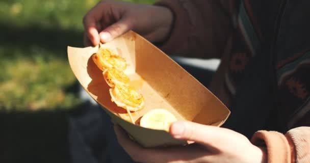 美丽的年轻女子在公园里吃街头食物 享受春天的阳光 女孩吃烤虾仁 高质量的4K镜头 — 图库视频影像