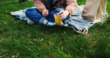 Güzel genç bir kadın parkta kokteyl içer, bahar güneşinin tadını çıkarır. Bahar limonatası. - Evet. Yüksek kalite 4k görüntü