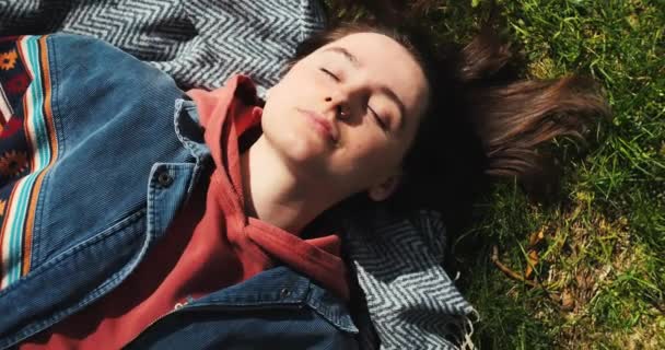 衣冠楚楚的女孩躺在绿草上 美丽的女人在公园里享受着阳光灿烂的春天 释放年轻成年女性的天性 快乐女人的画像 高质量的4K镜头 — 图库视频影像