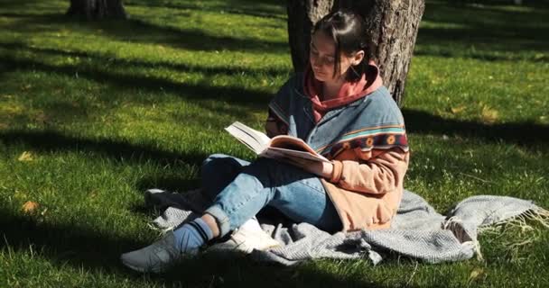年轻的成年女性在公园看书 在外面春天的阳光下看书 女孩喜欢看书 高质量的4K镜头 — 图库视频影像