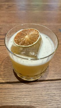 glass of lemon juice with ice cubes on wooden background