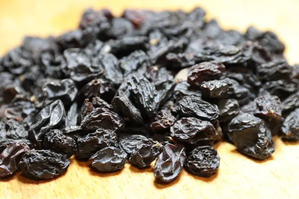 Kurutulmuş siyah kuru üzümler masada.