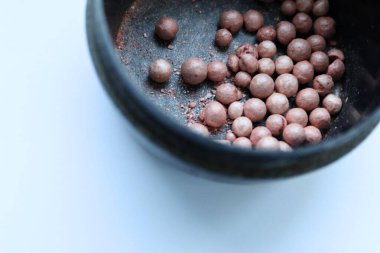 Siyah arka planda kaşıkla kasedeki kahverengi fasulyeler.