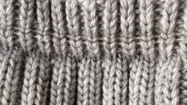 Beyaz arka planı olan gri örülü süveter, yakın plan. doku