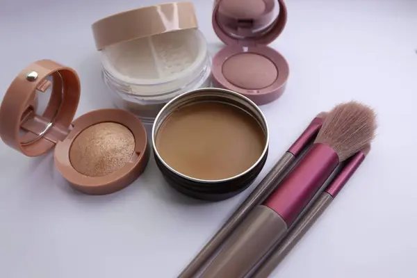farklı makyaj fırçaları, makyaj tozu ve beyaz arka planda pudra