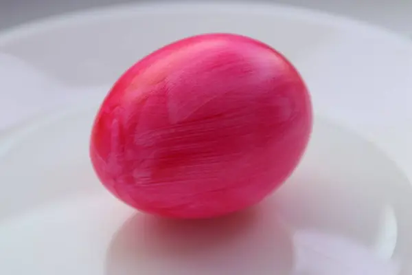 Beyaz tabakta pembe paskalya yumurtalarını yakın.