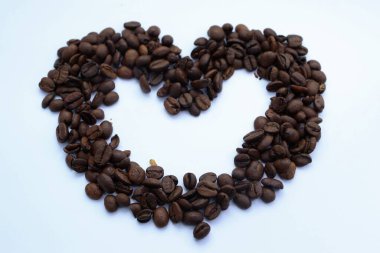 Beyaz arka planda kahve çekirdekleri ve kalp şekli