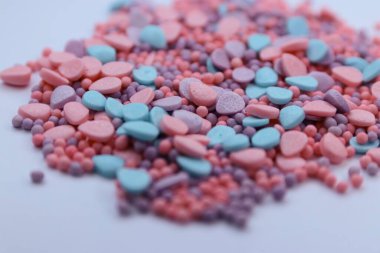 Beyaz arkaplanda renkli kalp şekilli şekerler.