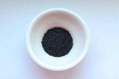 Açık arkaplanda seramik bir kasede siyah susam, üst manzara..