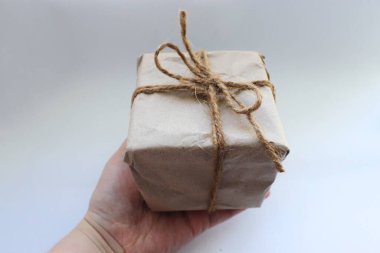 El işi ambalajında bir paket, turnikeyle bağlanmış, beyaz bir arka planda el ele tutulmuş.