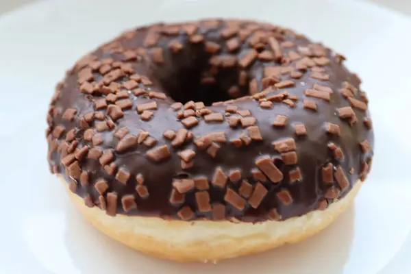 Jöleli donut, çikolatalı jöle ve çikolata parçacıkları, beyaz arka plana yakın.