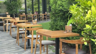 Parktaki yazlık kafe, ahşap masalar, yeşil çimenler, cam, açık hava eğlencesi için bir yer.