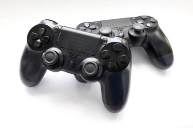 İki oyun kumandası kapanıyor, modern siyah oyun kontrolörleri - konsol için ergonomik oyun aksesuarları, beyaz arka planda oyun kontrolörleri, beyaz arkaplanda joystick 'ler, oyun pedleri