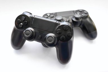 İki oyun kumandası kapanıyor, modern siyah oyun kontrolörleri - konsol için ergonomik oyun aksesuarları, beyaz arka planda oyun kontrolörleri, beyaz arkaplanda joystick 'ler, oyun pedleri
