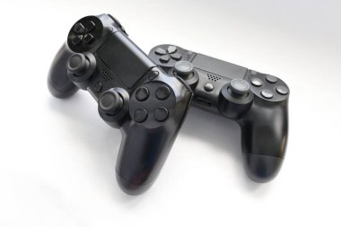 İki oyun kumandası kapanıyor, modern siyah oyun kontrolörleri - konsol için ergonomik oyun aksesuarları, beyaz arka planda oyun kontrolörleri, beyaz arkaplanda joystick 'ler, oyun pedleri