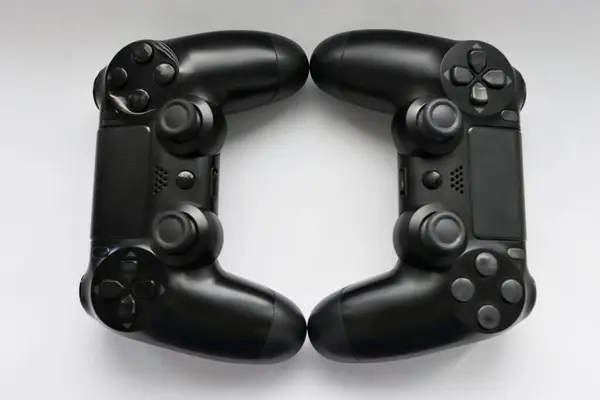 İki oyun kumandası kapanıyor, modern siyah oyun kontrolörleri - konsol için ergonomik oyun aksesuarları, beyaz arka planda oyun kontrolörleri, beyaz arkaplanda joystick 'ler, oyun pedleri