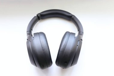 Beyaz zemin üzerinde modern siyah kablosuz kulaklıklar hareketliliğin ve teknolojik seçimin sembolü olarak